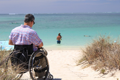 Muž na vozíku pred plážou .Obrázok od LonelyTaws z Pixabay 